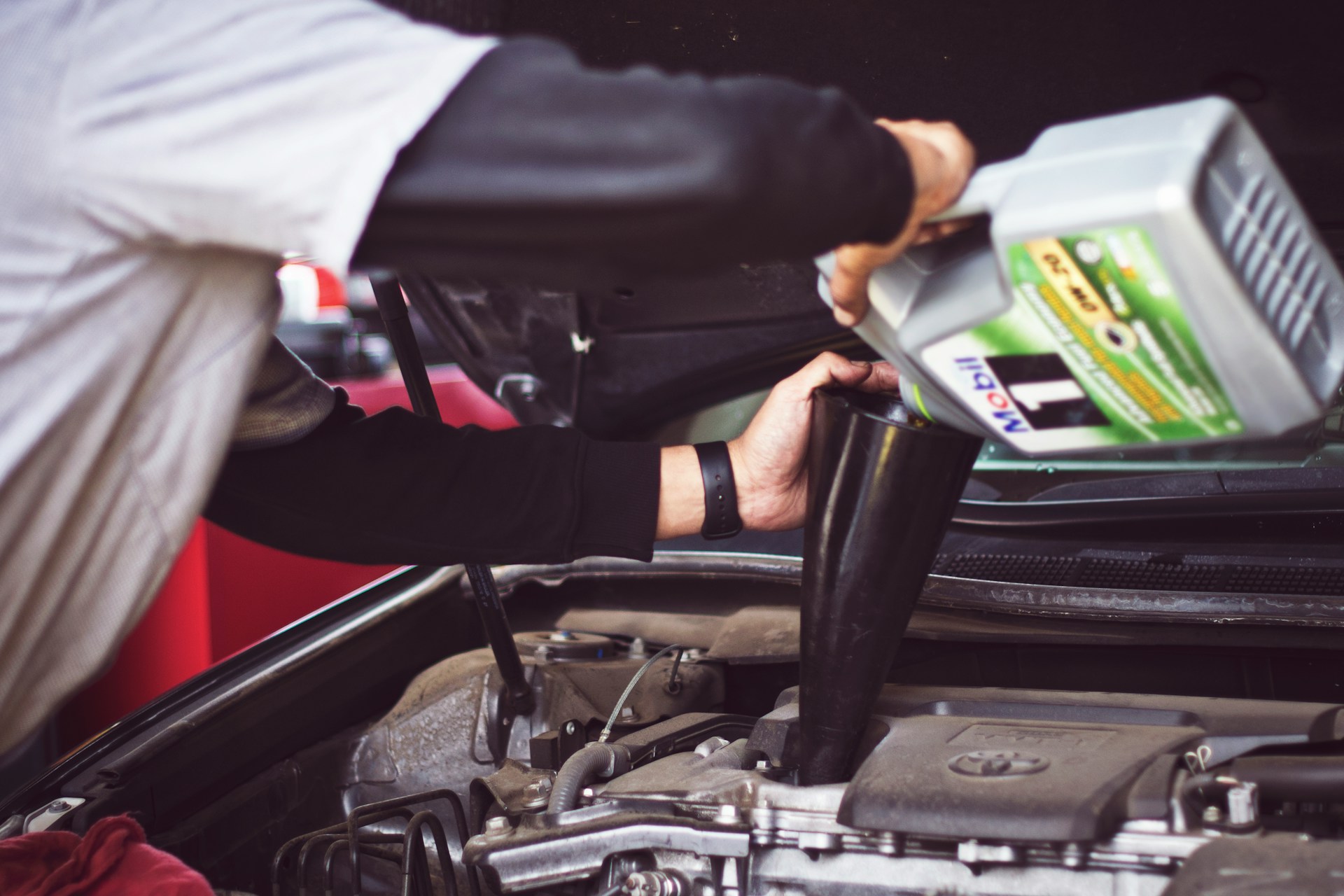 Man refilling motor oil on car engine bay